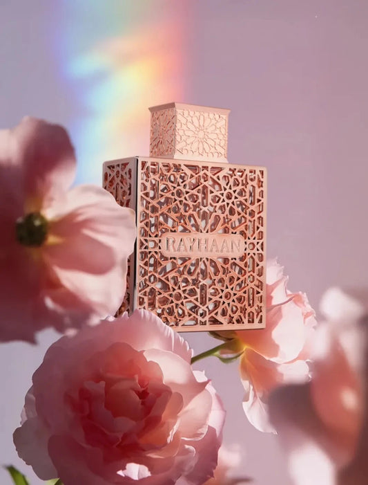 Rayhaan Divine Perfume bottle with intricate design surrounded by pink flowers and a rainbow effect