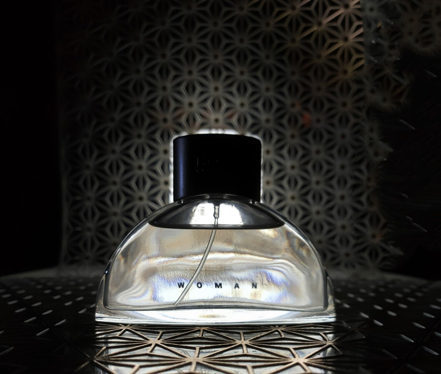 Perfume bottle labeled 'Woman' on a textured surface with a dark background