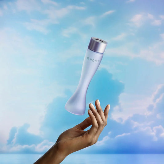 Hand holding a 'GHOST' product against a blue sky with clouds