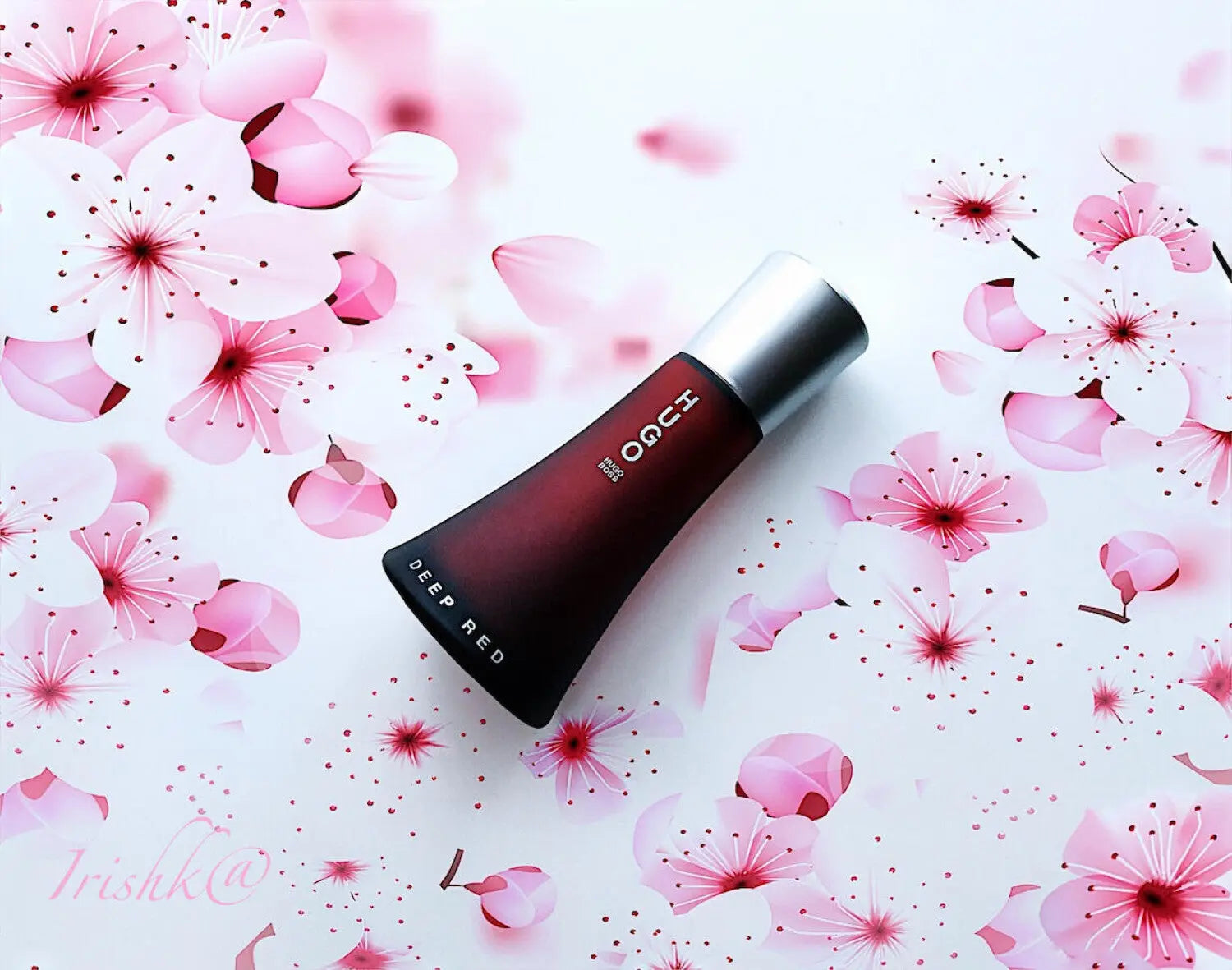 Red lipstick with silver cap on a background of pink flowers