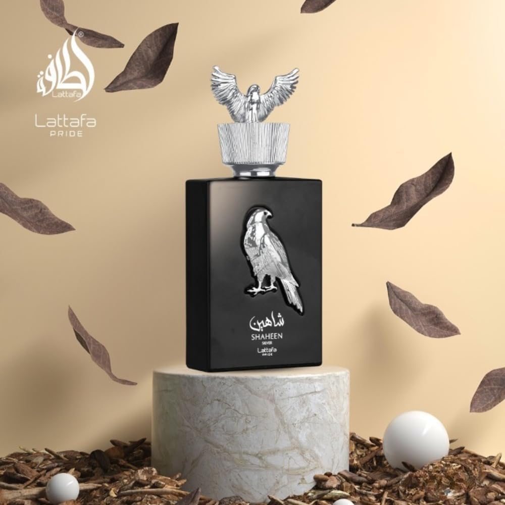 Lattafa Shaheen Silver Black perfume bottle with silver eagle design on a beige background with feathers and eggs.