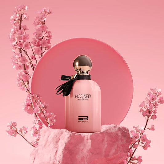 Pink perfume bottle with cherry blossoms on a pink background
