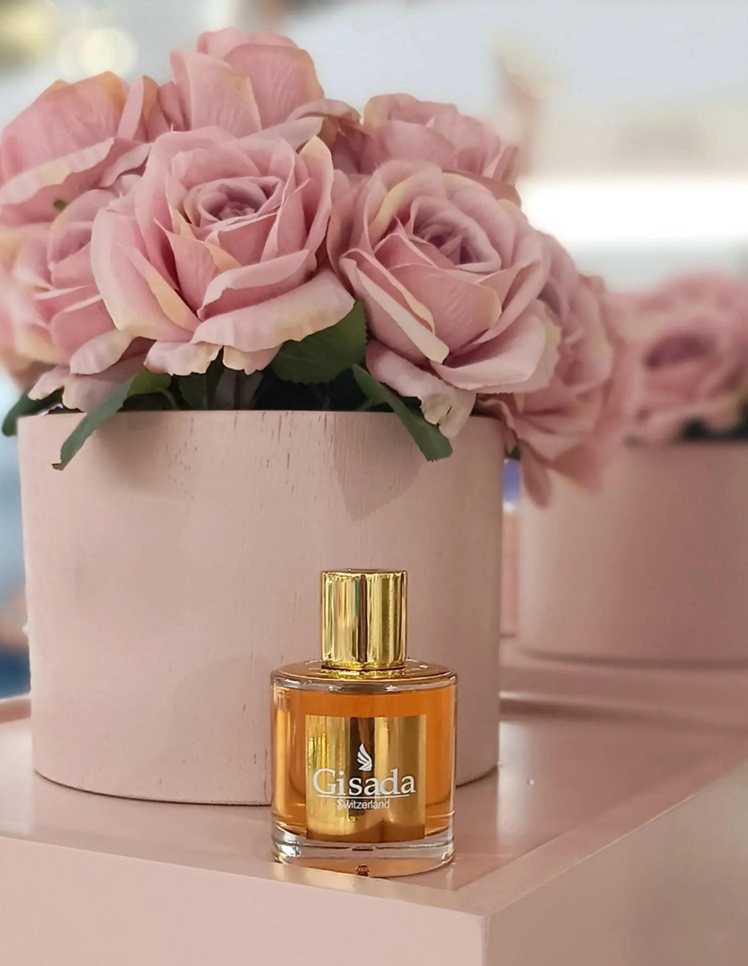 Gisada perfume bottle with pink roses in the background
