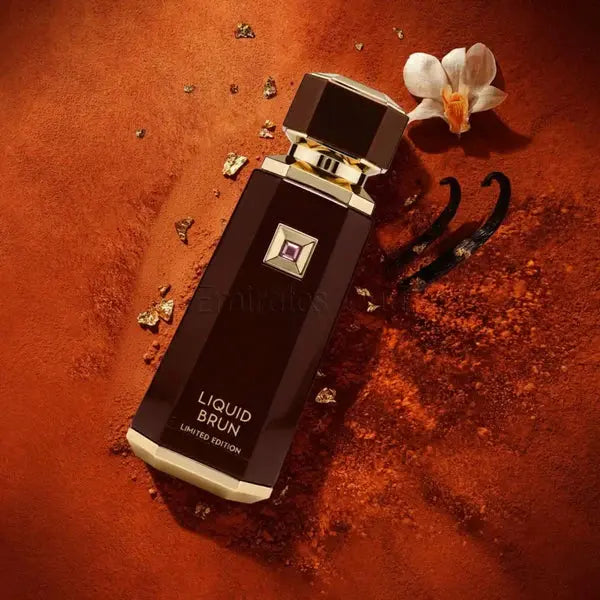 Perfume bottle labeled 'Liquid Brun' on a textured brown surface with flowers and gold elements.