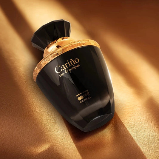 Black and gold Carino perfume bottle on a textured brown background