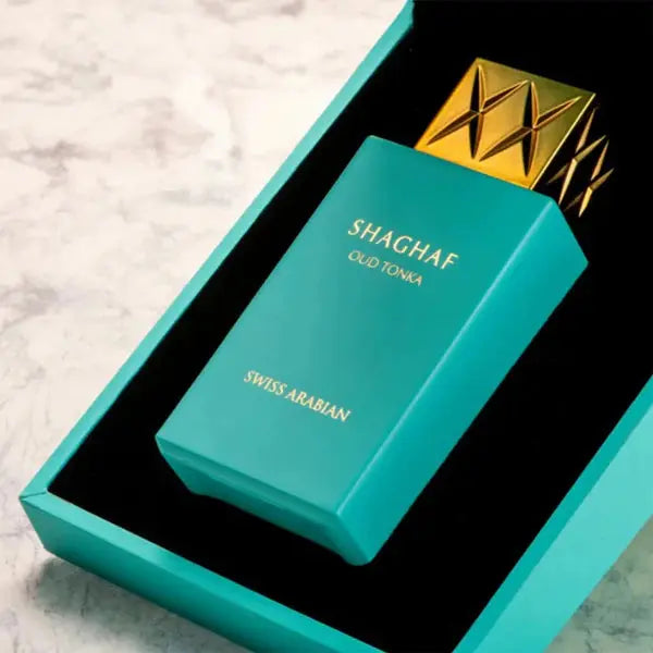 Teal perfume bottle with gold cap in a box on a light gray background