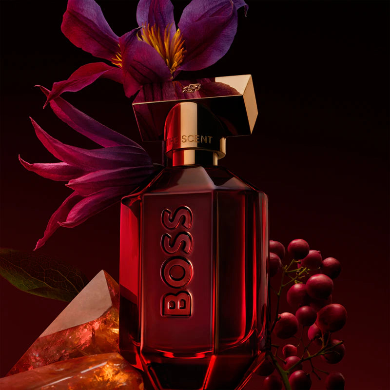 BOSS perfume bottle with purple flowers and grapes on a dark background