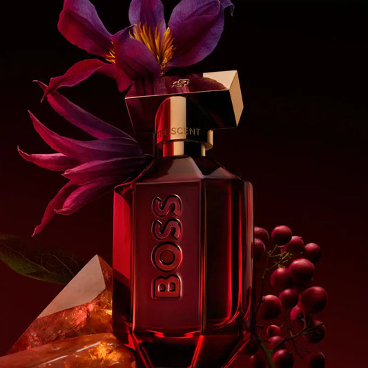 BOSS perfume bottle with purple flowers and grapes on a dark background
