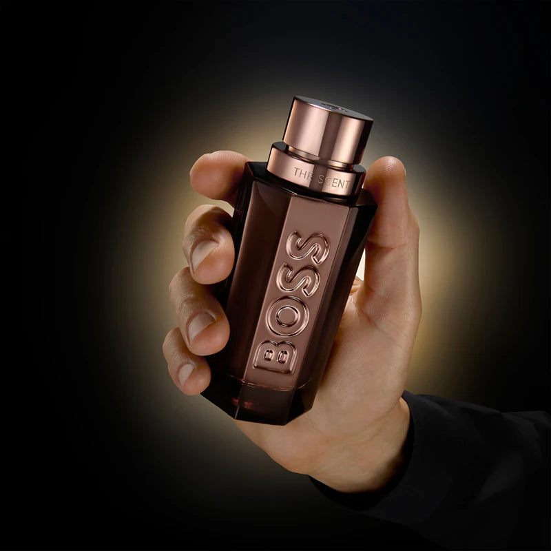 Hand holding a BOSS perfume bottle against a dark background