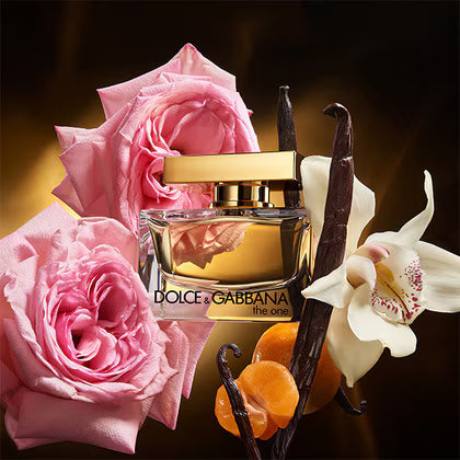 Dolce & Gabbana perfume bottle with pink roses, vanilla beans, and an orange on a dark background