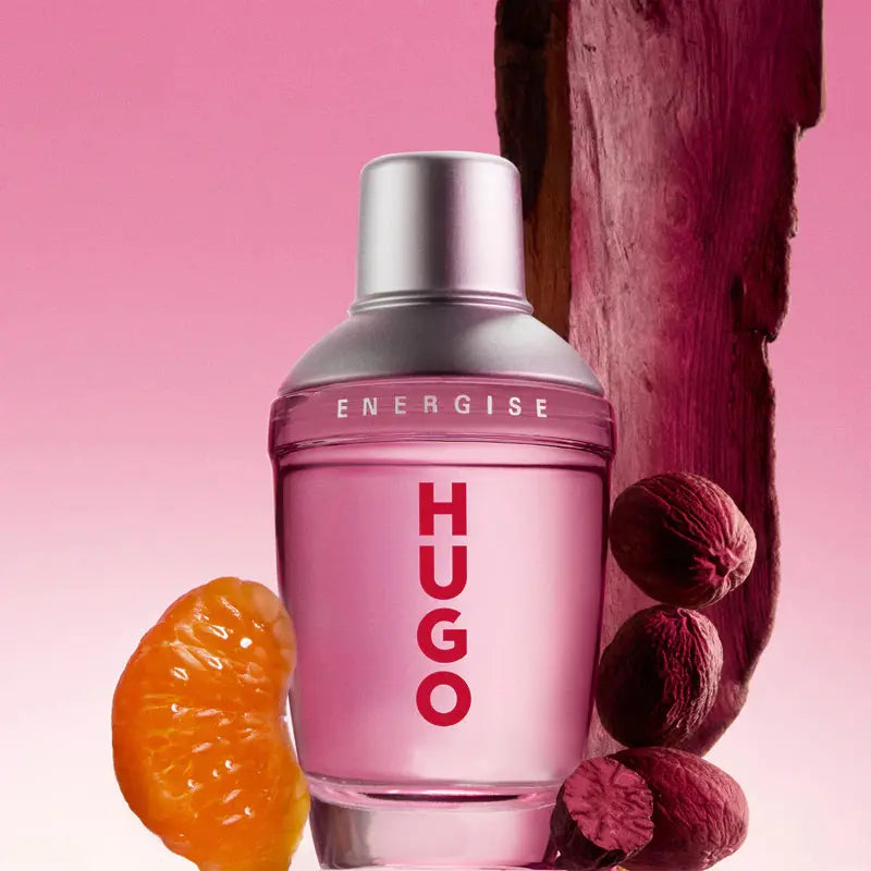Pink Hugo Energise perfume bottle with fruits on a pink background