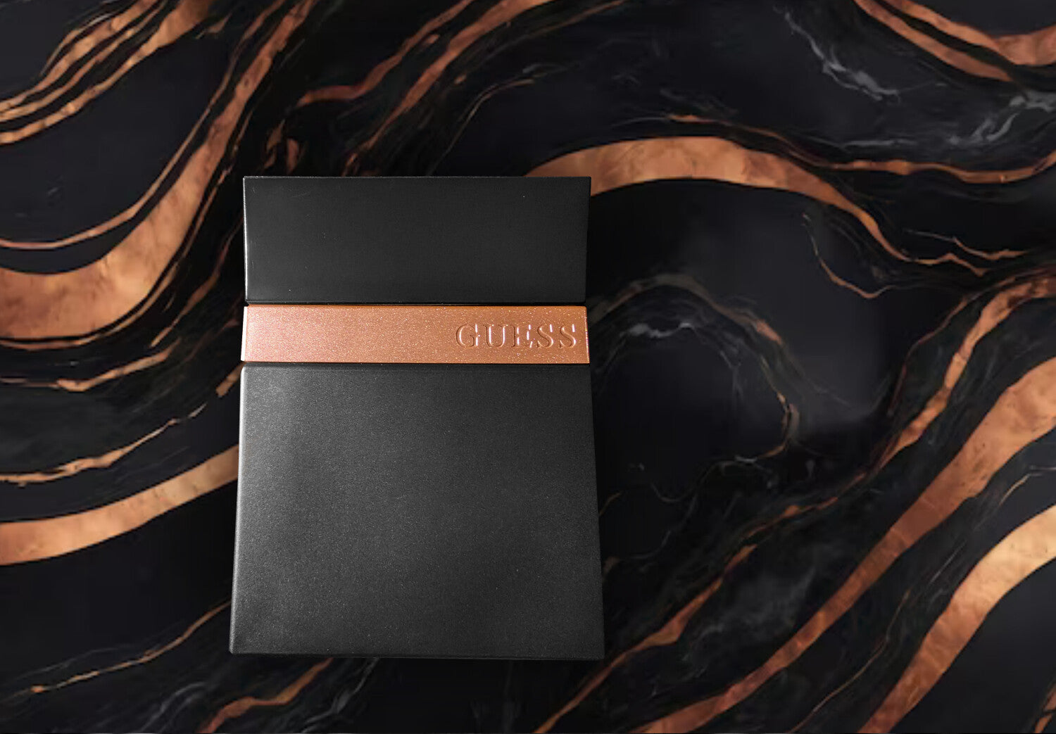 Black Guess notebook with a brown leather strap on a black and gold marbled background