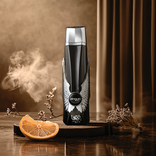 Zimaya Itqan Noir Black deodorant bottle with wings on a wooden surface with dried flowers and an orange slice.