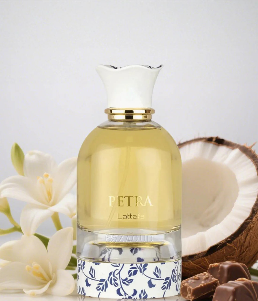 Perfume bottle labeled 'Petra' with coconut, flowers, and chocolate on a light background