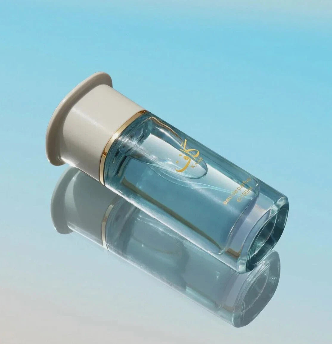 Ahmed Al Maghribi Kaaf Clear glass bottle with beige cap on a gradient blue background