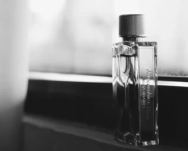 Perfume bottle on a reflective surface with a blurred background