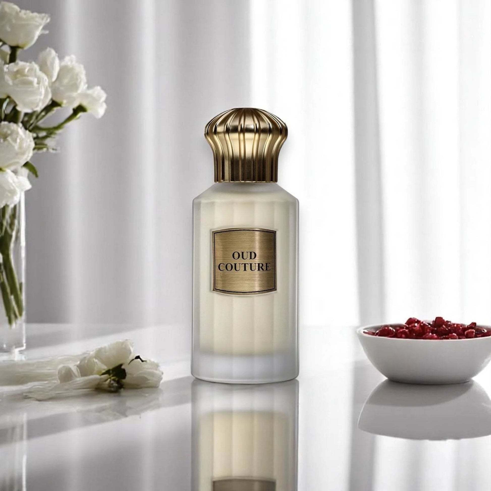 Ahmed Al Maghribi Oud Couture Perfume bottle labeled 'Oud Couture' on a reflective surface with white flowers and a bowl of red berries in the background.