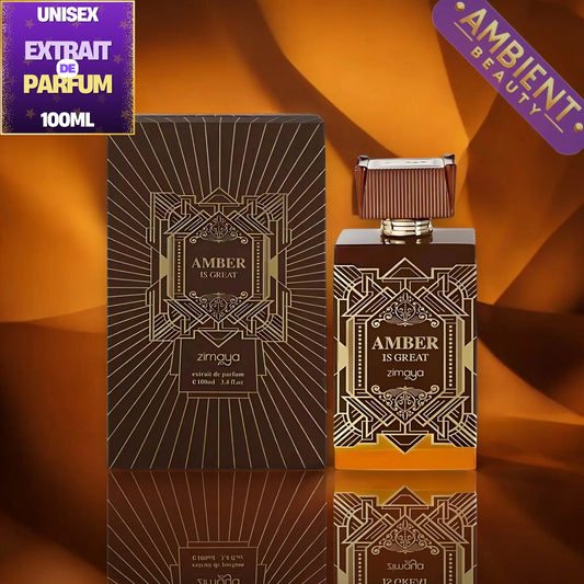 A 100ml bottle of zimoya Amber Is Great Extrait De Parfum next to its matching dark brown and gold geometric-patterned box, set against a warm orange-brown draped background with a reflection below.